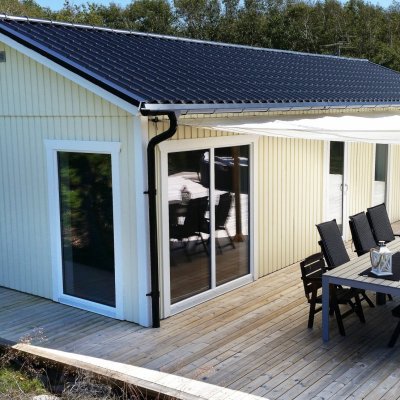 Gult fritidshus med trädäck